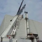 2 cranes inspections two white chimneys at side of warehouse
