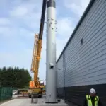 Crane placing a new chimney using heavy chains