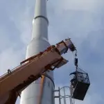 men in crane lift inspecting steel chimney